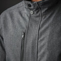 Close-up of charcoal grey Stormtech jacket showing stand collar, snap buttons, and angled chest zip pocket