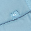 Close-up of powder blue polo placket with four-hole button on woven reinforcement patch and overlock seam detail