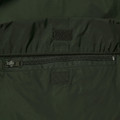 Forest green packable jacket close-up showing zip pocket, velcro patch panels and lightweight ripstop shell
