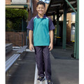 Boy wearing navy gaberdine long pants with double knee panels in a school courtyard setting