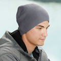 Man wearing a steel grey cable knit beanie with fine ribbed texture, styled with a grey zip-up jacket outdoors