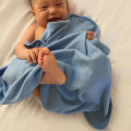 Baby wrapped in cornflower blue hooded organic blanket with soft fleece texture