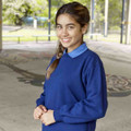 Young girl wearing a royal blue crew neck fleece sweatshirt with ribbed cuffs in an outdoor school setting