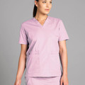 Woman wearing a dusty pink short-sleeve V-neck scrubs top with two front patch pockets