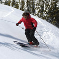 Red waterproof system jacket with hood worn skiing in snowy mountain conditions