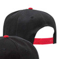 Black snapback cap with red undervisor and adjustable snap closure, structured six-panel crown