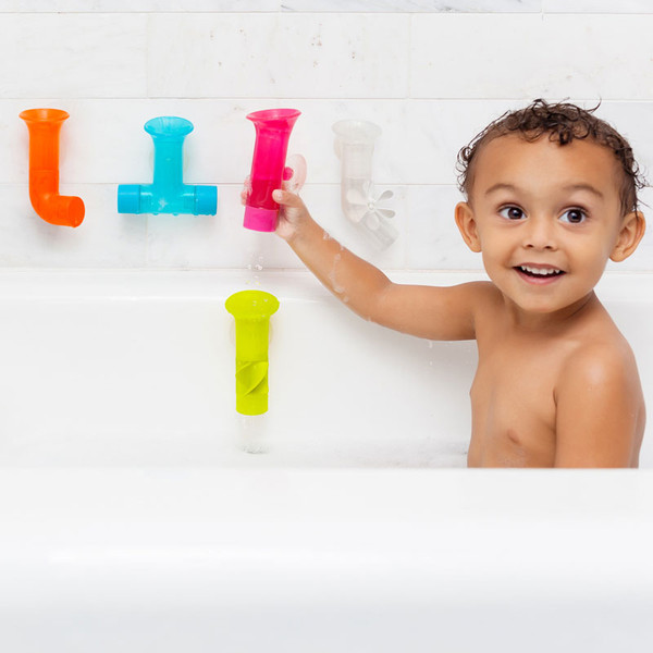 Child playing with colourful bath pipe toys in orange, teal, hot pink, white and lime green on bathroom tiles