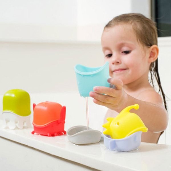 Child holding aqua blue whale bath toy with colourful sea creature stacking toys on bath edge