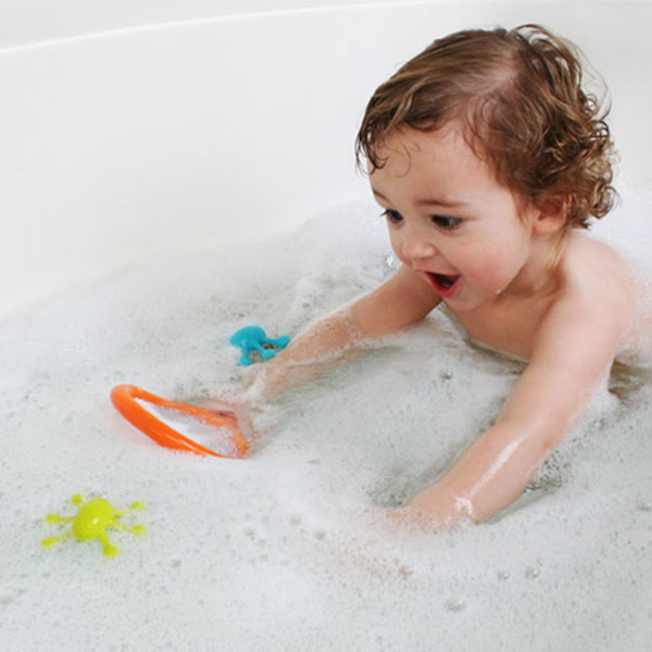 Toddler playing in bubble bath reaching for orange net with teal and yellow floating bug toys