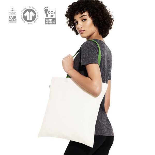 Natural cotton tote bag with lime green handles worn over shoulder against charcoal grey tee