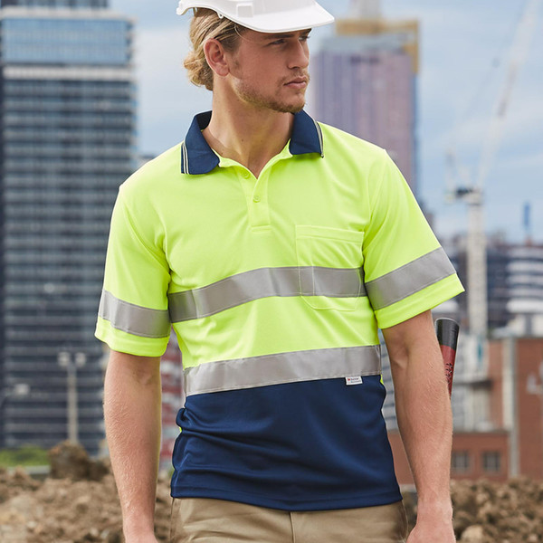 Man on construction site wearing hi-vis yellow and navy two-tone polo with silver reflective tape bands