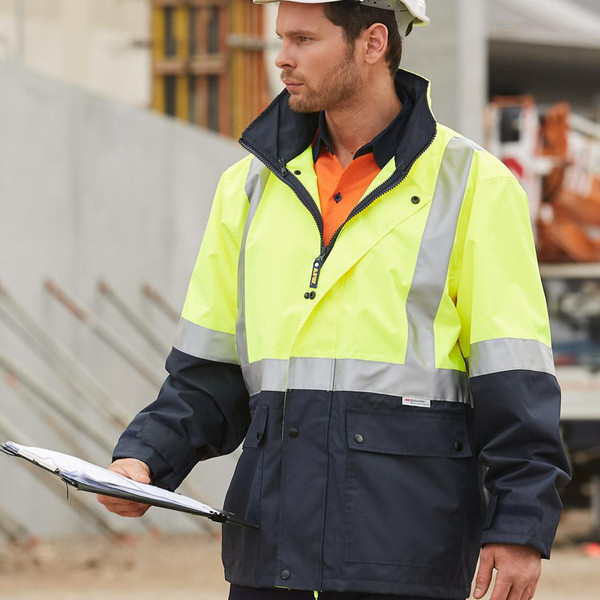 Man on construction site wearing fluoro yellow and navy two-tone hi-vis jacket with 3M reflective tape bands