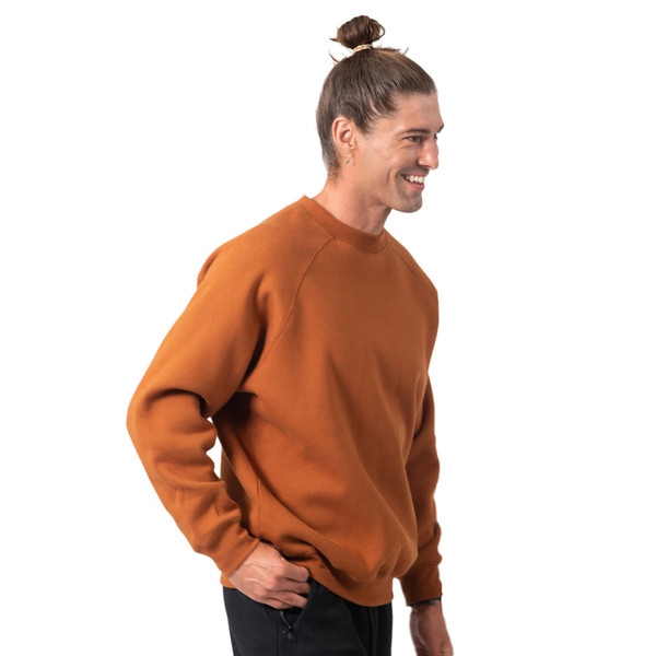 Burnt orange crew neck fleece sweater with ribbed cuffs and hem, shown on male model in side profile