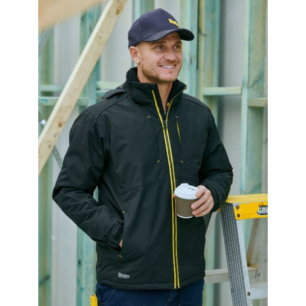 Black waterproof jacket with yellow contrast zipper and pocket details, worn with navy cap