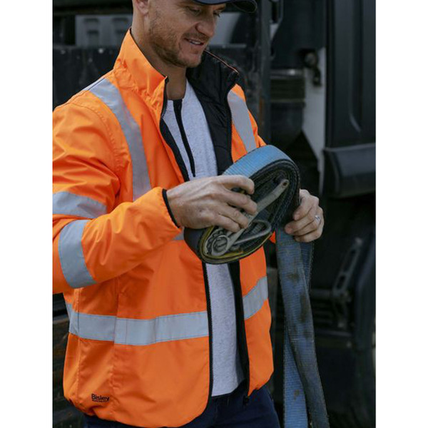 High visibility orange puffer jacket with silver reflective tape and black reversible side shown on model