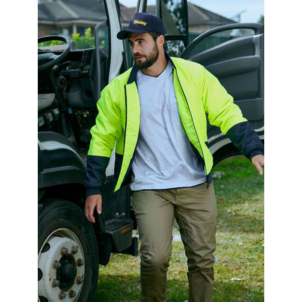 Man beside truck wearing yellow and navy hi vis bomber jacket with contrast sleeves and padded body