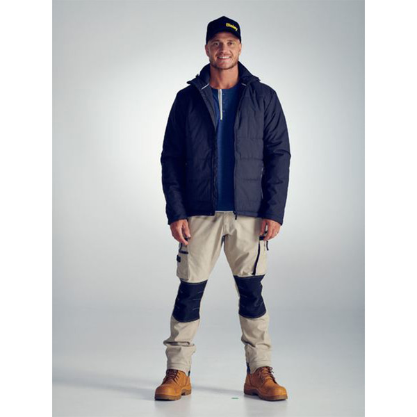 Navy quilted puffer jacket with adjustable hood and zip front, worn with stone cargo pants