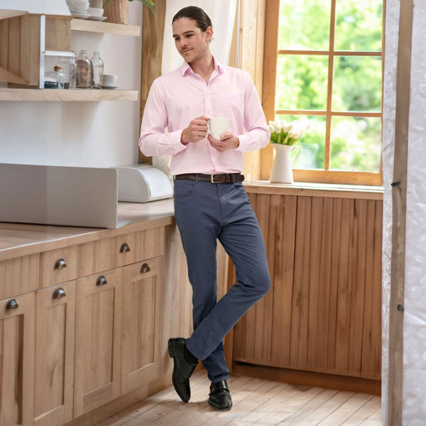 Man wearing slate blue chino pants with light pink business shirt in casual setting