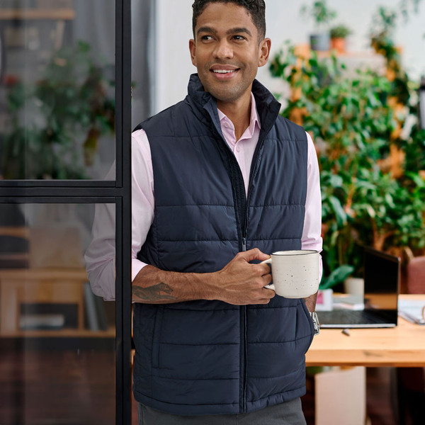 Navy quilted puffer vest with full zip front and stand collar worn over light pink shirt