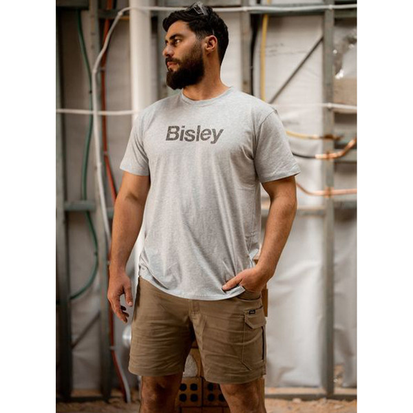 Man wearing a grey marle crew neck cotton tee with a large chest logo print, styled on a worksite