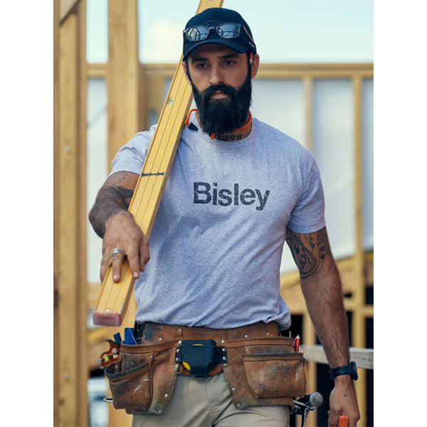 Tradie on construction site wearing a light grey marle crew neck tee with dark chest logo print