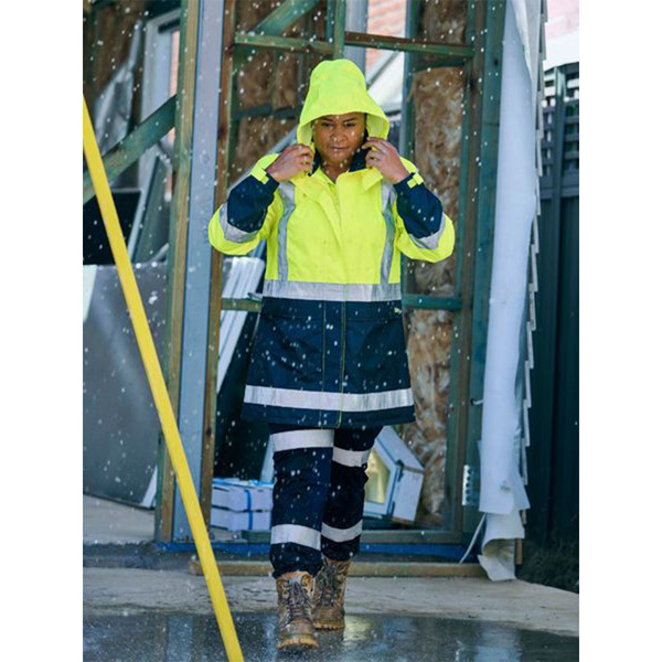 Woman on wet worksite wearing yellow and navy hi vis rain jacket with hood up and reflective tape panels