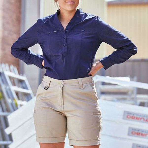 Stone beige stretch cotton work shorts with belt loops, zip fly, and functional pockets paired with navy work shirt