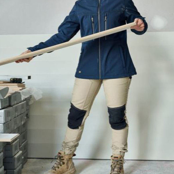 Navy softshell jacket with zippered pockets worn over stone stretch work pants with navy knee panel reinforcements