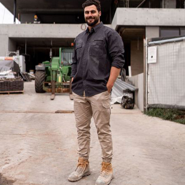 Man at construction site wearing charcoal long sleeve work shirt with chest pockets and rolled sleeves