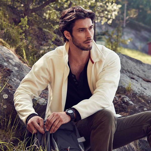 Man wearing cream double-face jacket with collar, layered over black shirt in outdoor setting