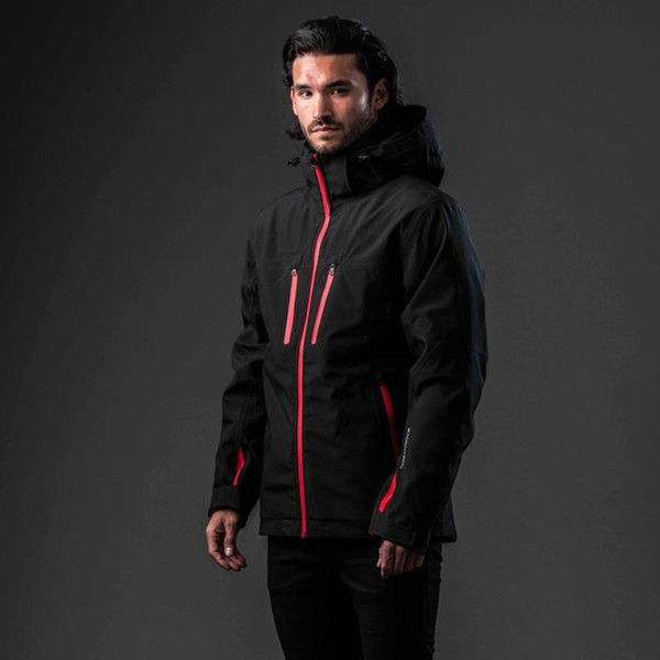 Male model wearing black technical 3-in-1 shell jacket with red contrast zip pullers, chest pockets and side panel detailing