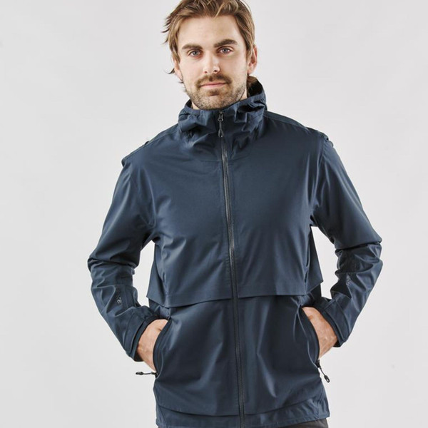 Man wearing a midnight navy technical shell jacket with structured hood, full-length zip, and cape-style back panel