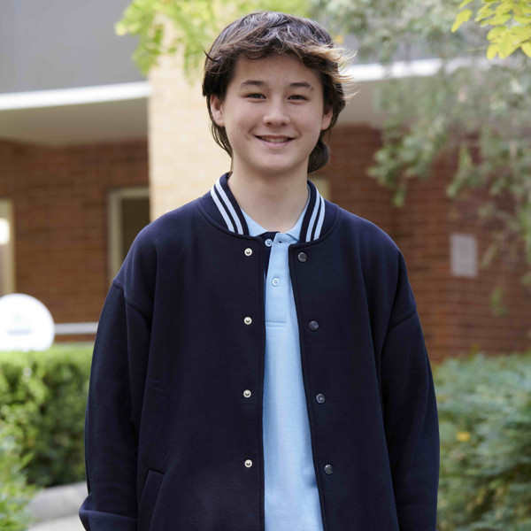 Youth wearing navy fleece bomber jacket with white stripe rib collar and stud front, styled over a light blue polo outdoors