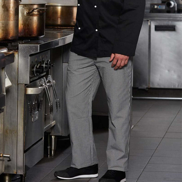 Black and white houndstooth check chef's work pants worn in a commercial kitchen setting