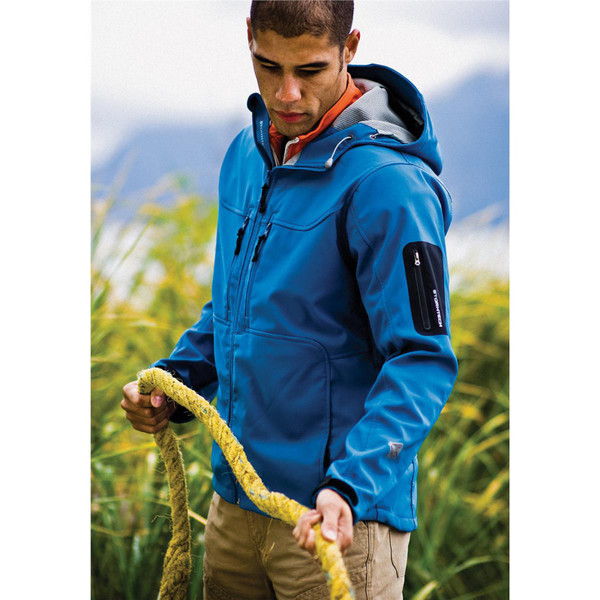 Man wearing electric blue Stormtech three-layer softshell jacket with hood, chest zip pockets, and sleeve utility pocket outdoors