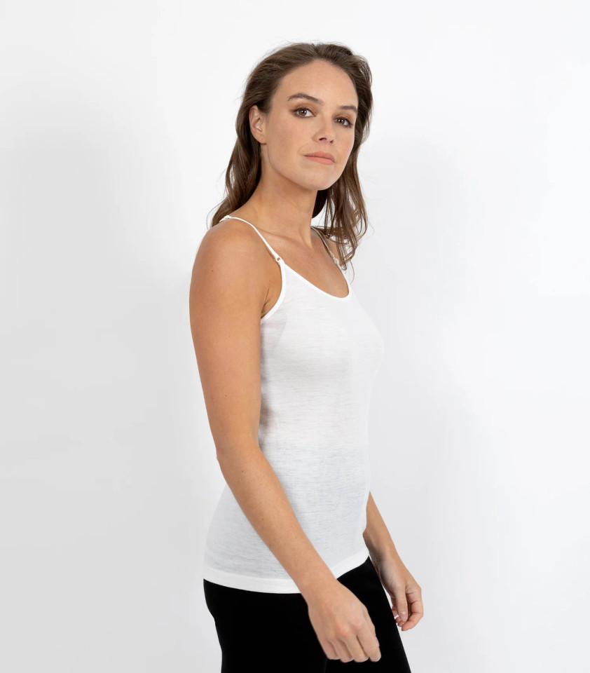 Woman wearing white merino wool singlet with narrow shoulder straps and a relaxed scoop neckline, side profile view