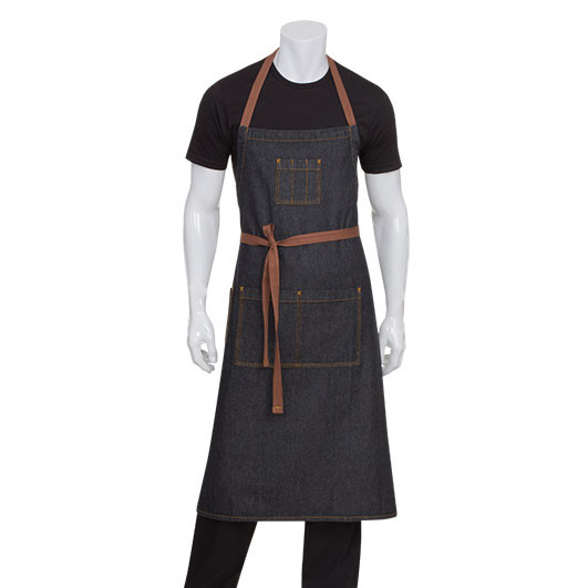 Dark indigo denim bib apron with tan leather straps, chest pocket, and twin waist pockets, worn by male model