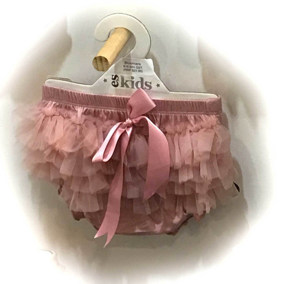 Dusty pink baby bloomers with layered chiffon ruffle tiers and satin bow, hanging on wooden hanger