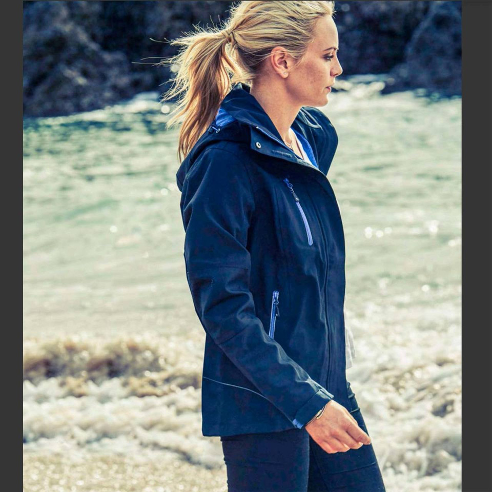 Navy blue ladies waterproof shell jacket with hood and chest zip pocket worn outdoors