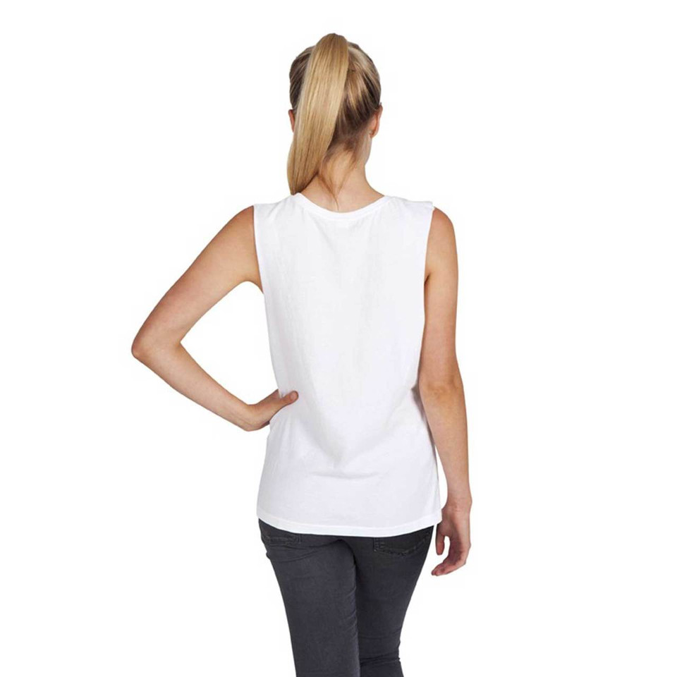 Woman wearing white sleeveless muscle tee tank, rear view, dropped armholes, smooth back panel, paired with charcoal pants