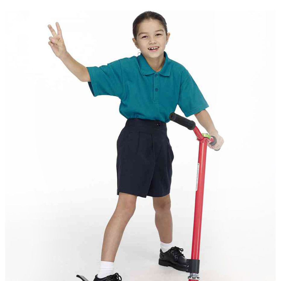 Young girl wearing tailored navy school shorts with teal polo shirt, showing classic pleated front design