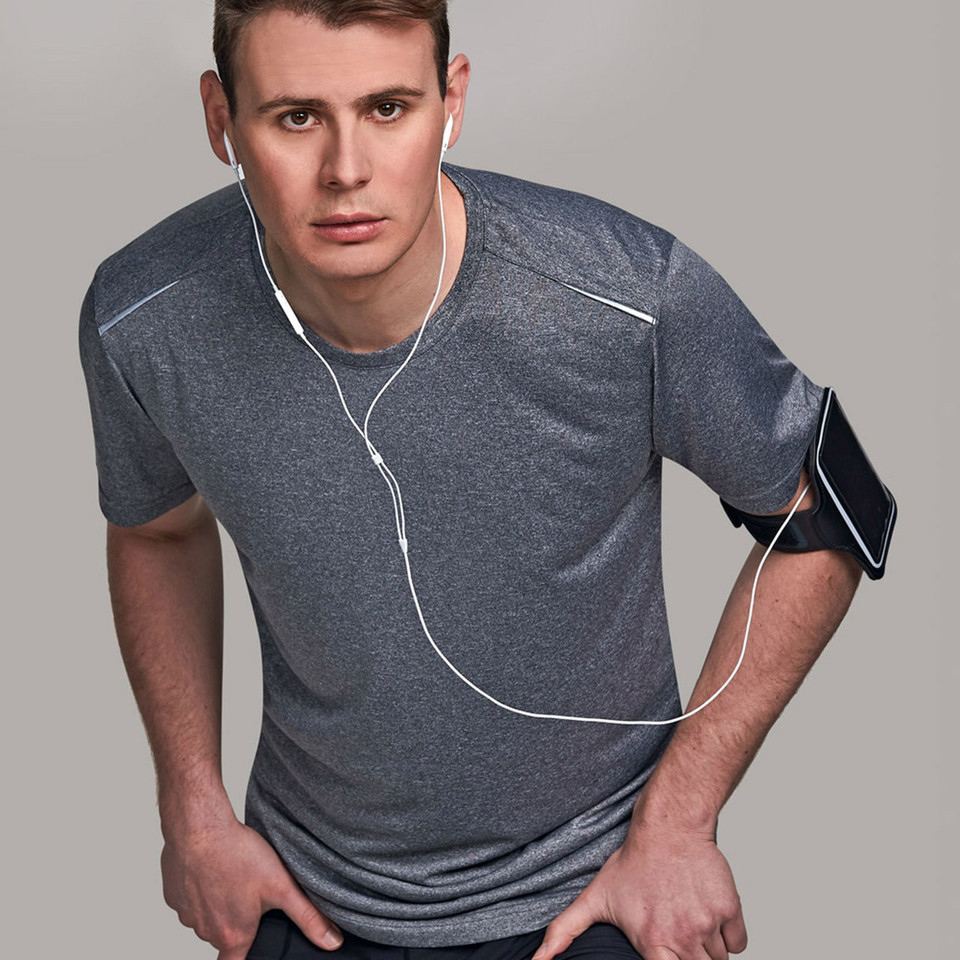 Man wearing charcoal marle quick-dry tee with reflective piping detail across chest and shoulders