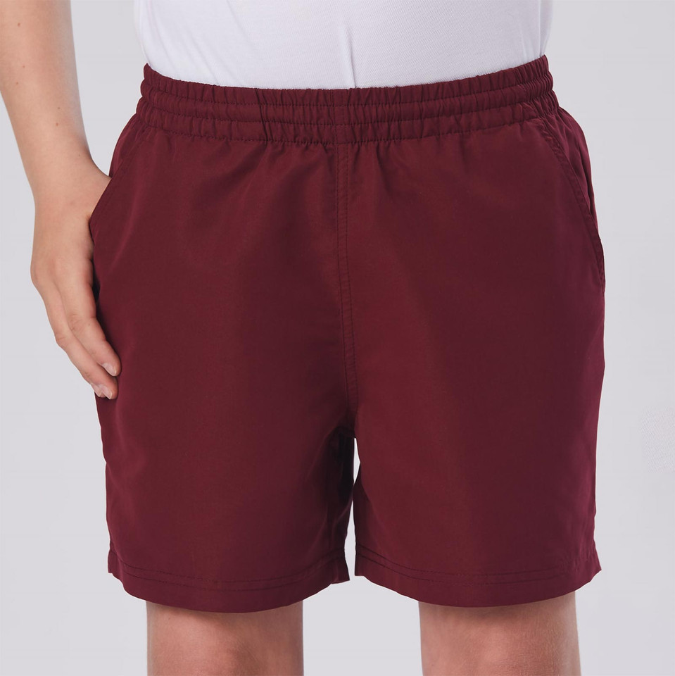 Kid wearing maroon microfibre sports shorts with elasticated waist and side pockets