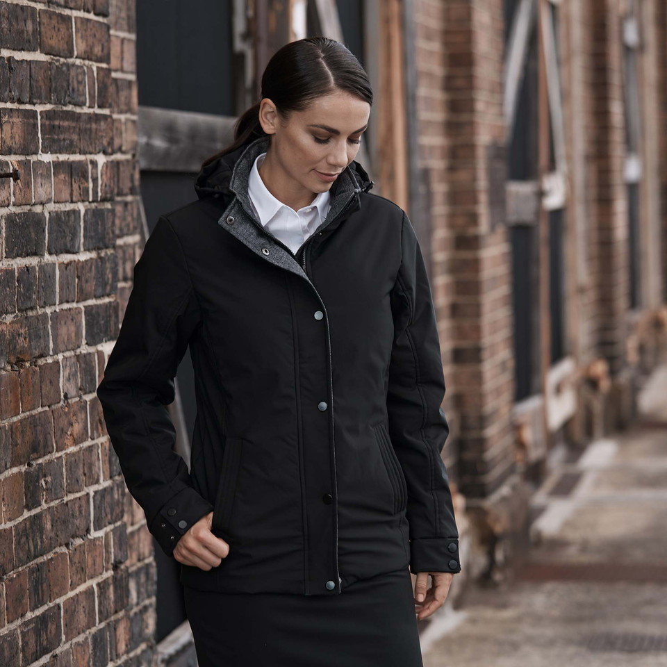 Black water-resistant jacket with hood, front zipper closure, and snap buttons, worn over white collared shirt
