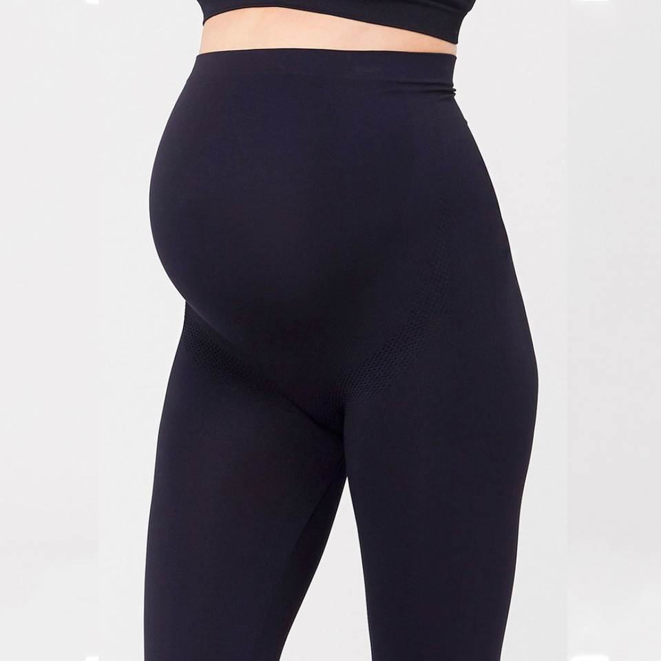 Model wearing black seamless maternity leggings with wide over-bump support panel, smooth finish