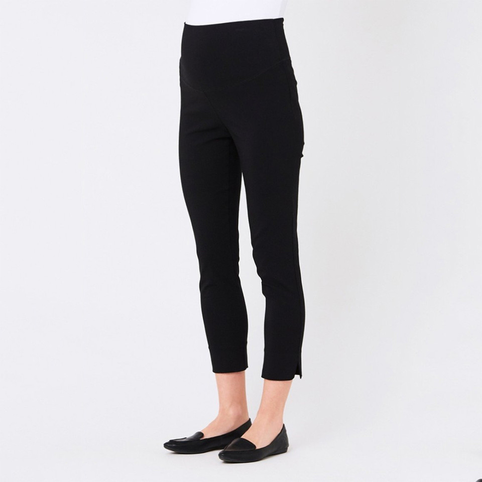 Model wearing black stretch capri pants with wide waistband and slim cropped leg with side slit hem