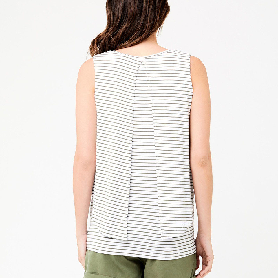 Model wearing white and navy stripe sleeveless tank, rear view showing swing back pleat detail, paired with olive trousers