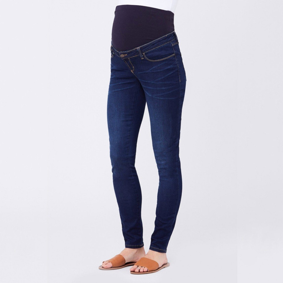 Model wearing indigo blue maternity jeggings with dark navy over-bump panel and slim-leg fit