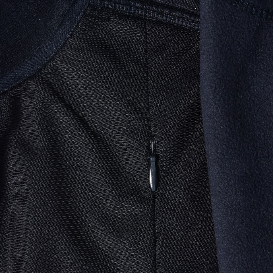 Close-up of navy softshell jacket lining showing interior zip pocket detail and contrast fleece panel