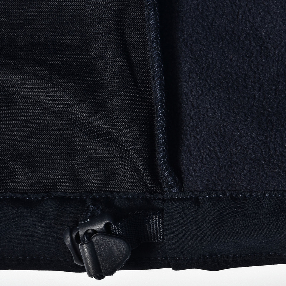 Close-up of navy softshell jacket hem zip detail showing contrast fleece lining and woven outer panel